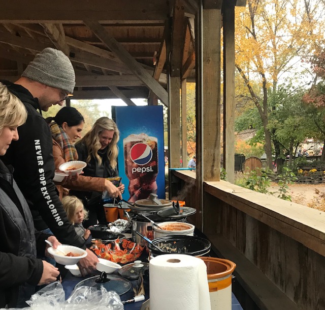 Associates and families gather at an outdoor fall chili feed — food, warmth, and good company